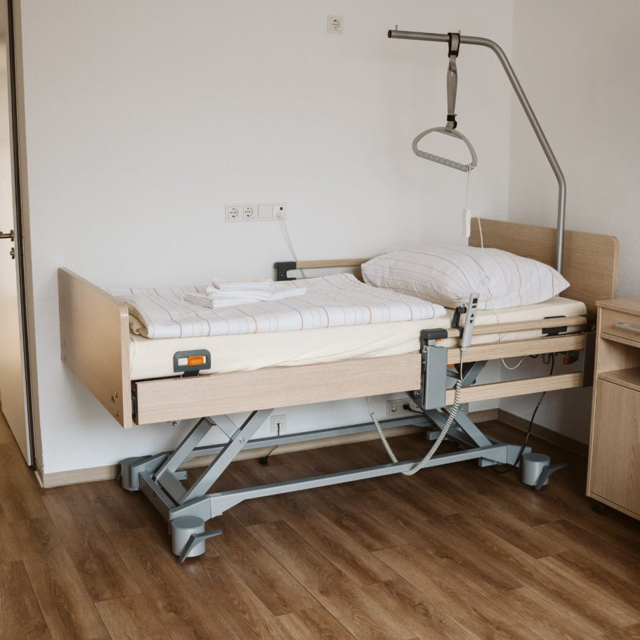 Ein höhenverstellbares Krankenhausbett in einem minimalistischen Zimmer.