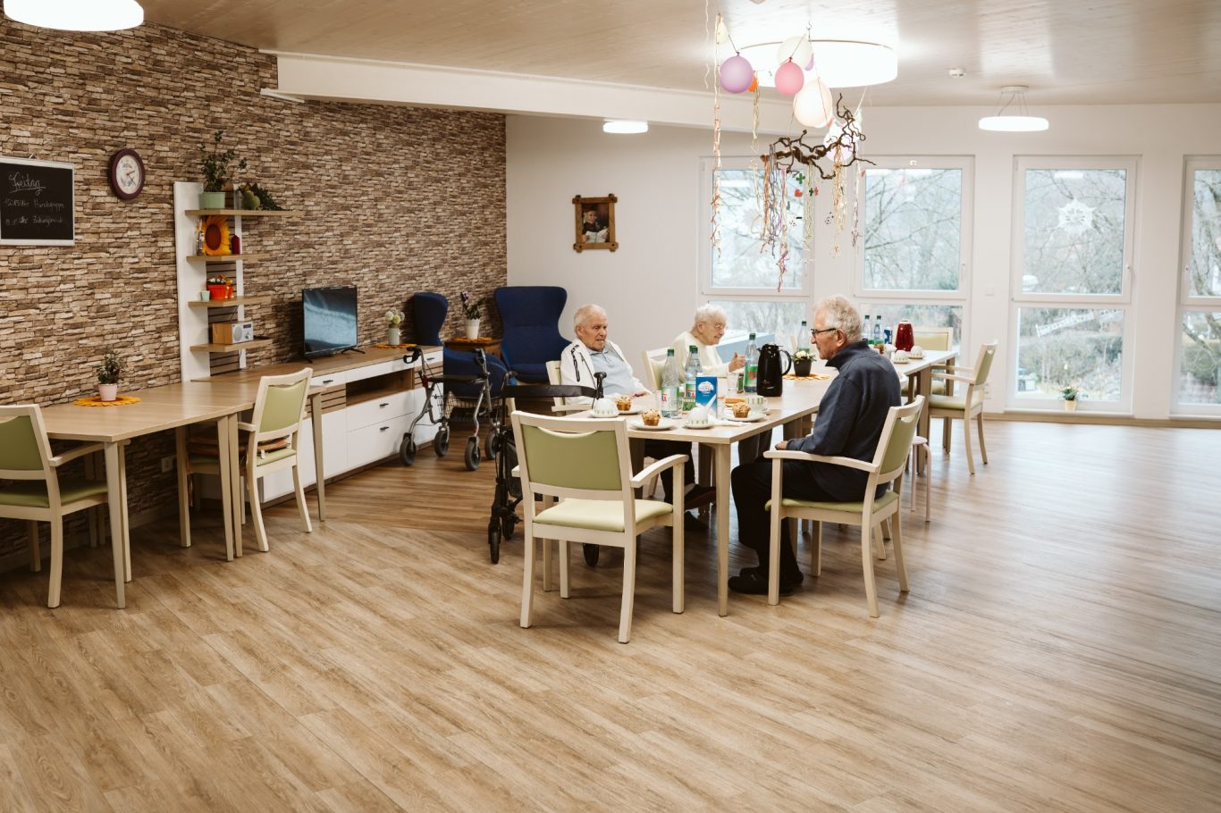 Ein helle, einladende Gemeinschaftsräume mit Senioren an einem Tisch.