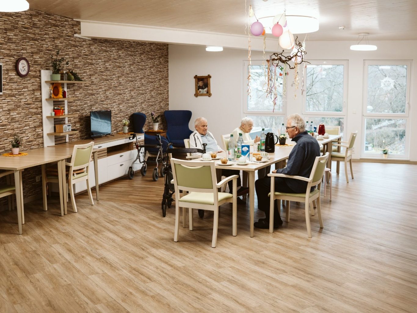 Ältere Menschen sitzen an einem Tisch in einem gemütlichen, hellen Raum.