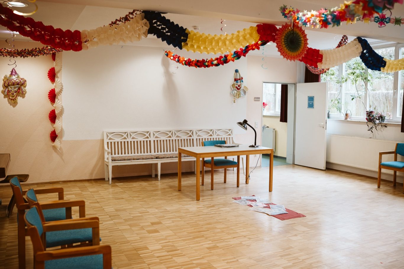 Heller Raum mit Tischen, Stühlen und festlicher Dekoration an der Decke.