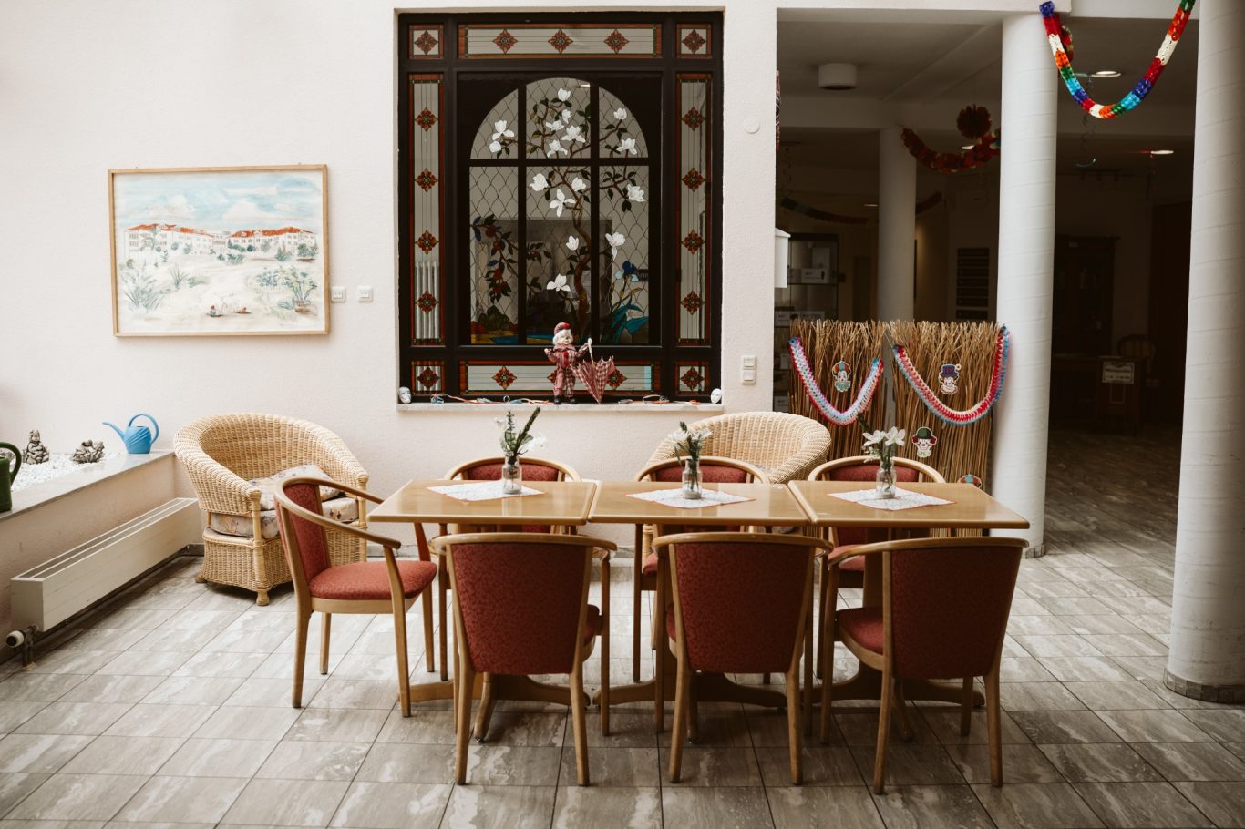Ein heller Essbereich mit Holztisch und Stühlen, dekoriert mit Blumen und Girlanden.