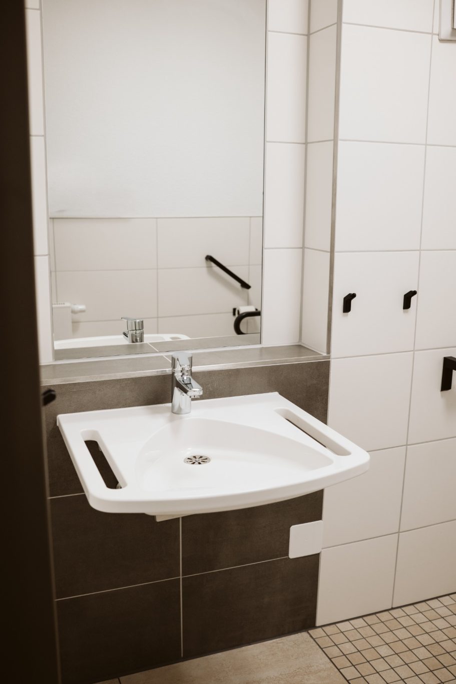 Moderne Badezimmer mit Waschbecken, Spiegel und glänzenden Armaturen.