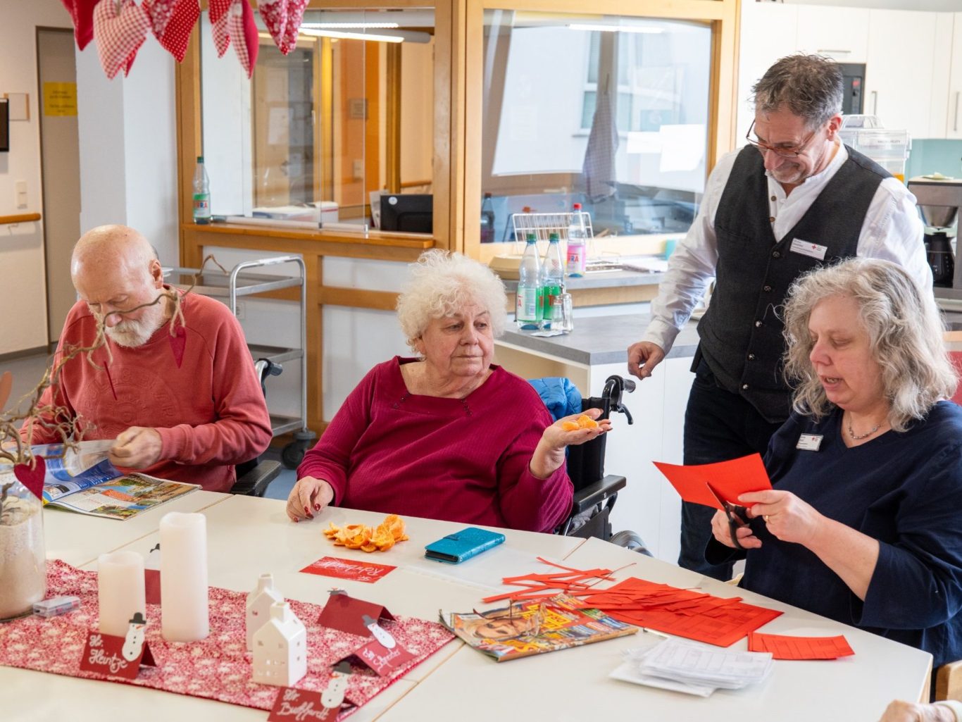 Vier Personen in einem Gemeinschaftsraum, die gemeinsam basteln und Spaß haben.