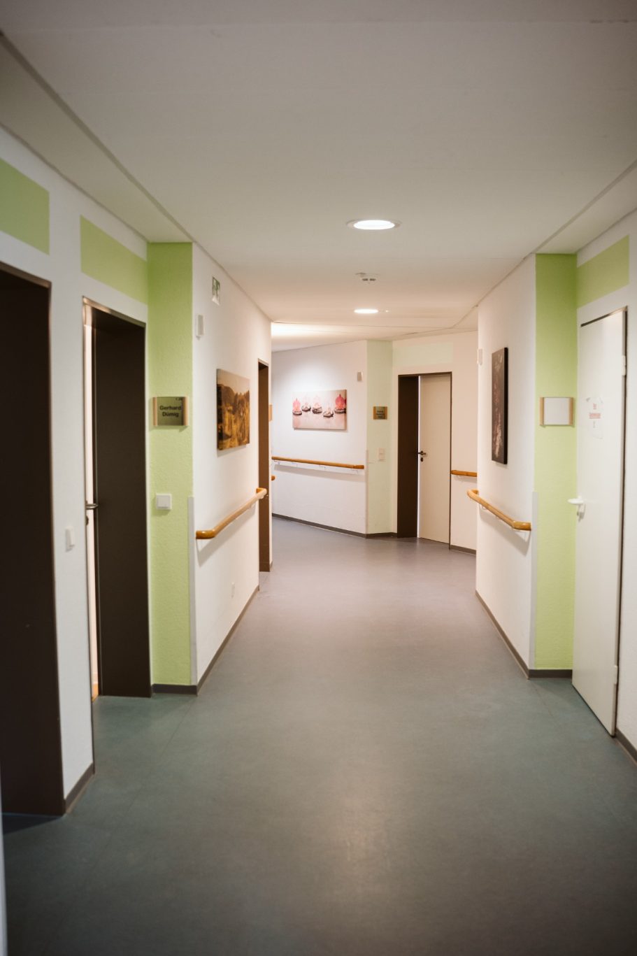 Heller Flur mit Türen, sanften Farben und Bildern an den Wänden.