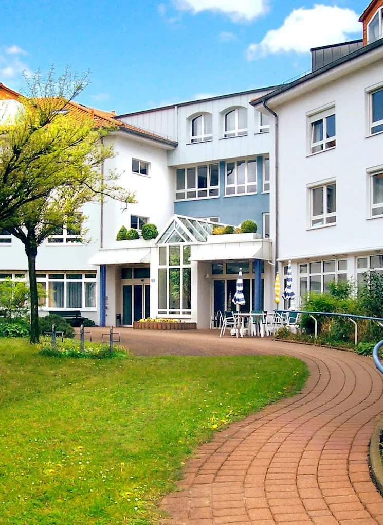 Moderne Wohngebäude mit Garten und geschwungener Gehweg. Heller Himmel im Hintergrund.
