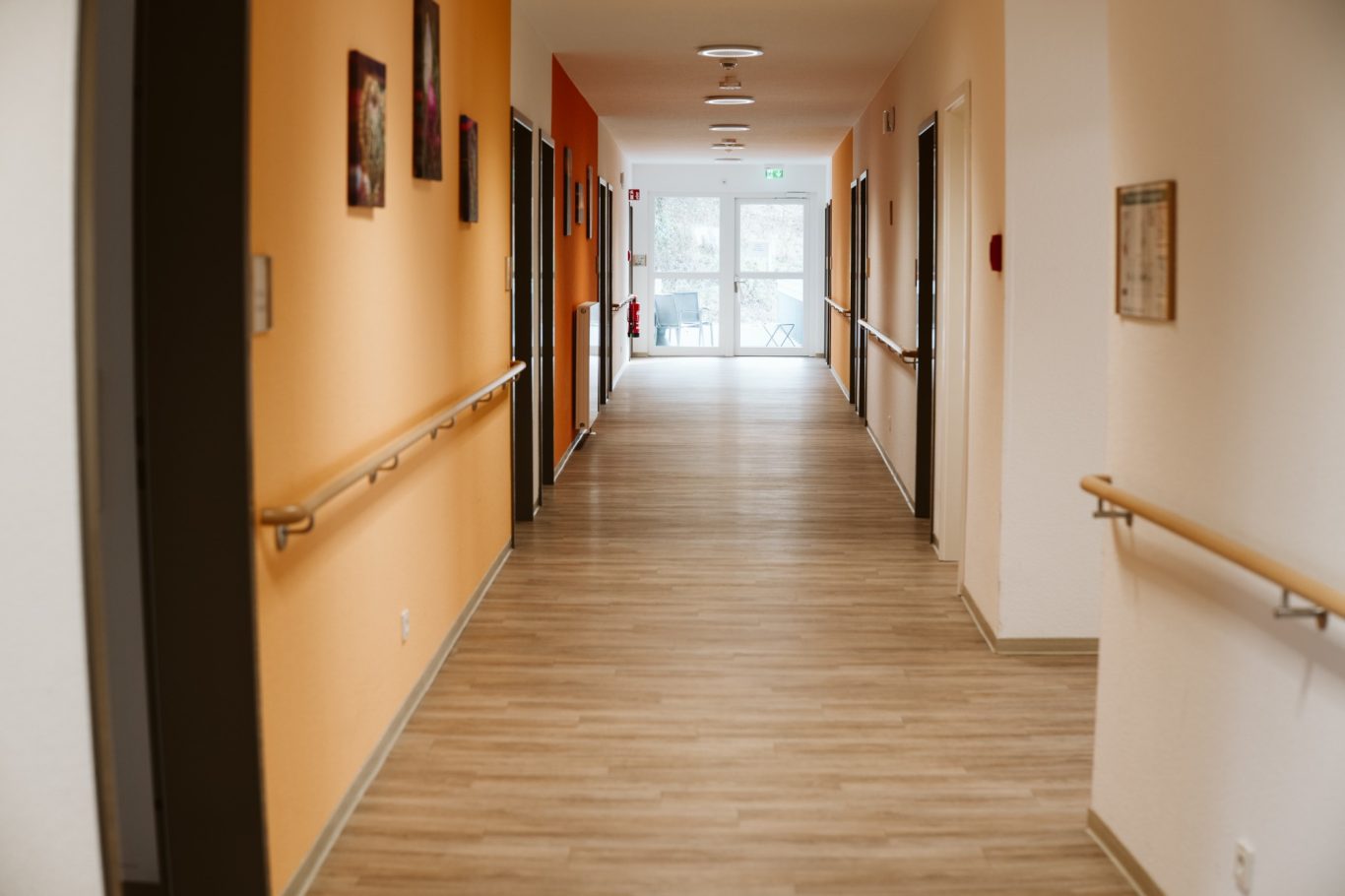 Ein heller, breiter Flur mit orangefarbenen Wänden und Türrahmen.